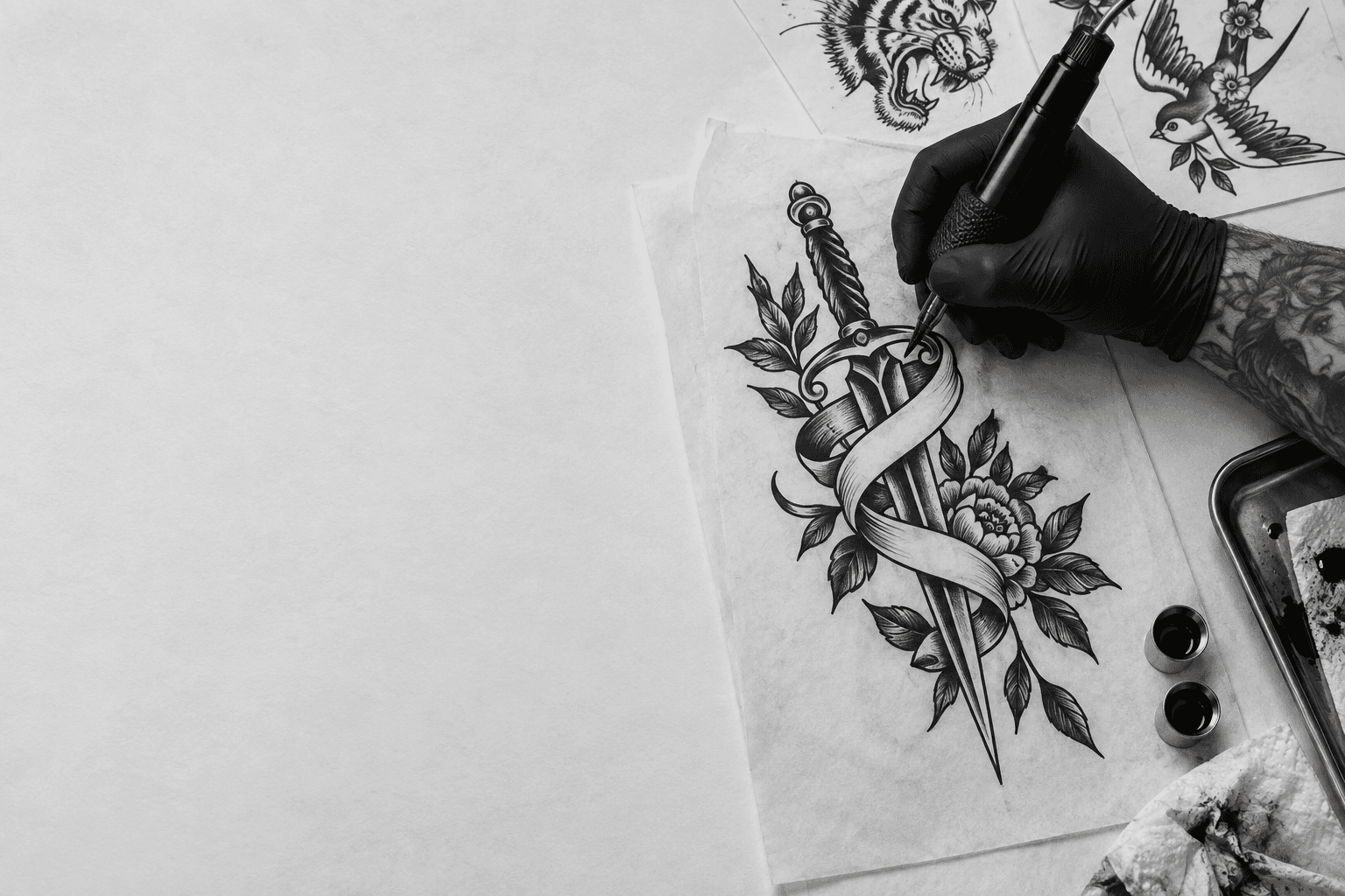 Blackwork dagger flash being drawn by a tattoo artist